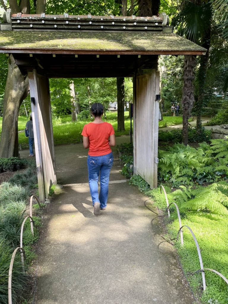 The author walking through a traditional Japanese wooden gate leading into the peaceful 'World Garden' at Musée Albert-Kahn, a hidden gem near Paris in Boulogne-Billancourt.